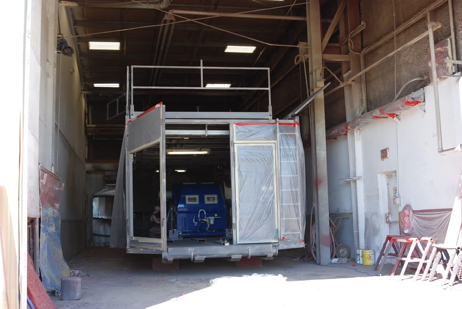 A primed and partially masked drilling rig
                pumphouse, in a workshop.